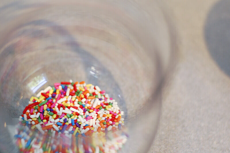 Rainbow sprinkles in the bottom of a flower vase.