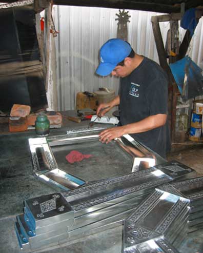 Mexican artist making traditional punched tin mirror.