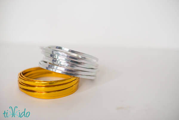 Coils of gold and silver flat craft wire on a white background.