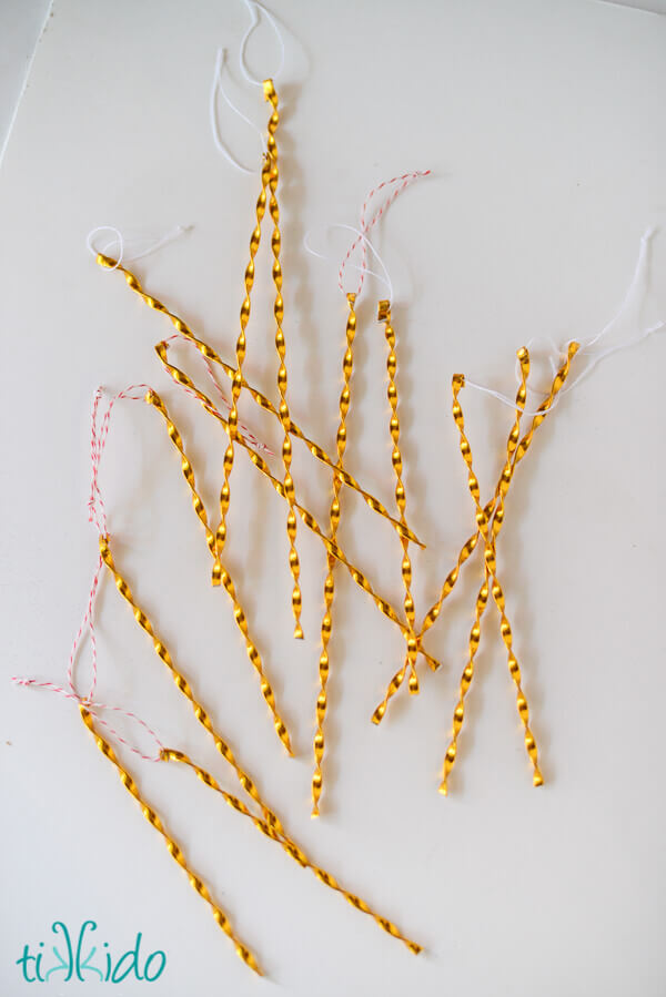 Gold colored Victorian Tinsel Ornaments on a white surface.