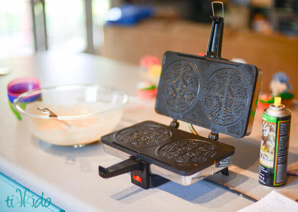 Krumkake wafer cookie iron on counter next to bowl of batter.