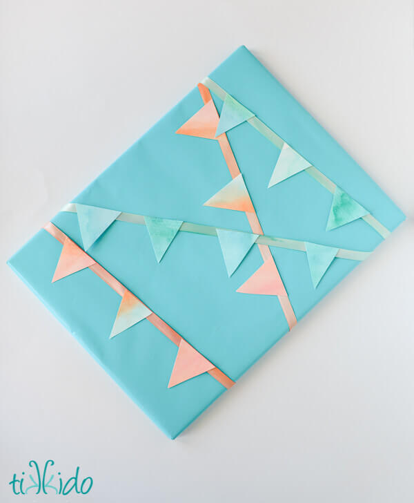Painted ribbon and watercolor painted paper made into mini bunting used to wrap a present.