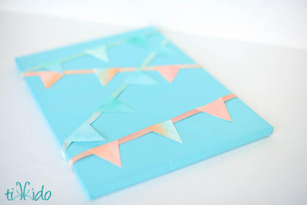 Painted ribbon and watercolor painted paper made into mini bunting used to wrap a present.