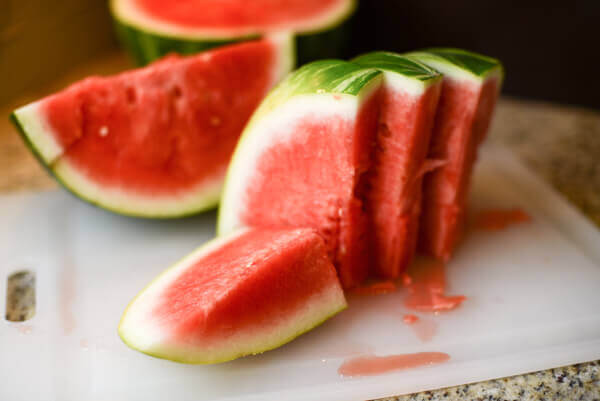 Slices of watermelon on a white cutting board.