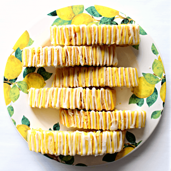 Lemon biscotti drizzled with white and yellow lemon glaze, on a plate painted with lemons.