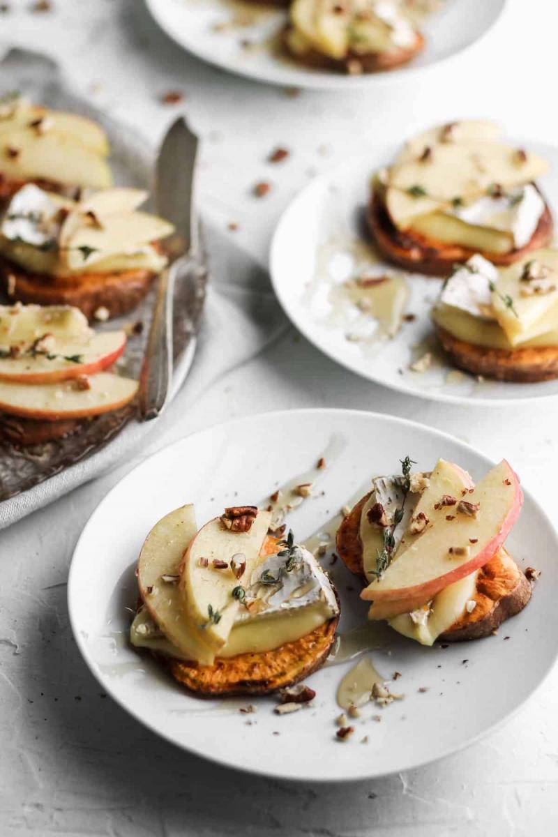 Apple and brie sweet potato crostini on small white plates.