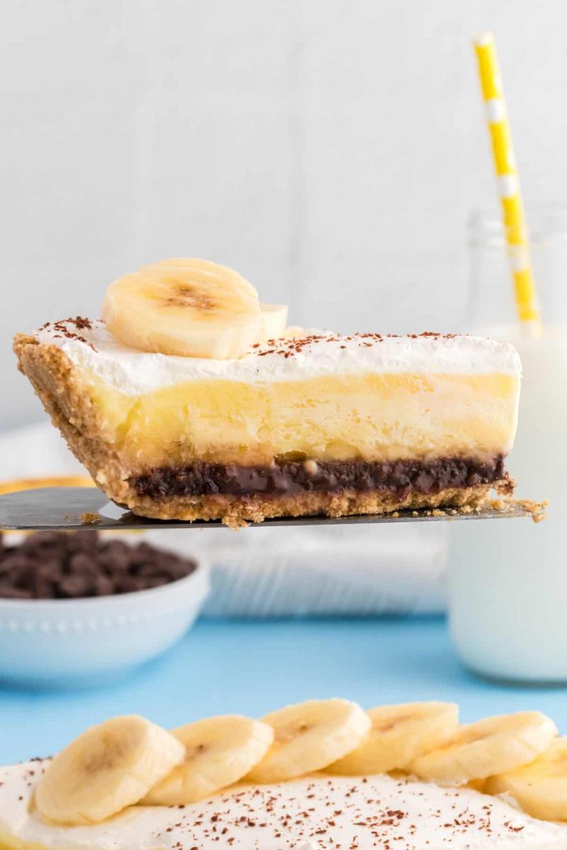 Slice of banana fudge pie being lifted above the rest of the pie on a pie server.