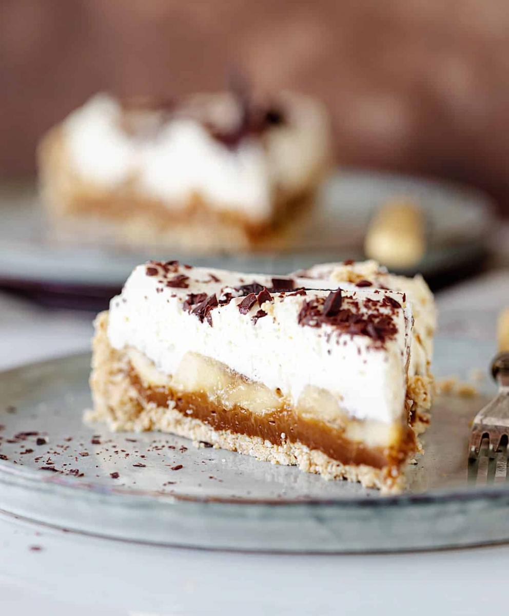 Slice of banoffee pie on a clear glass plate.