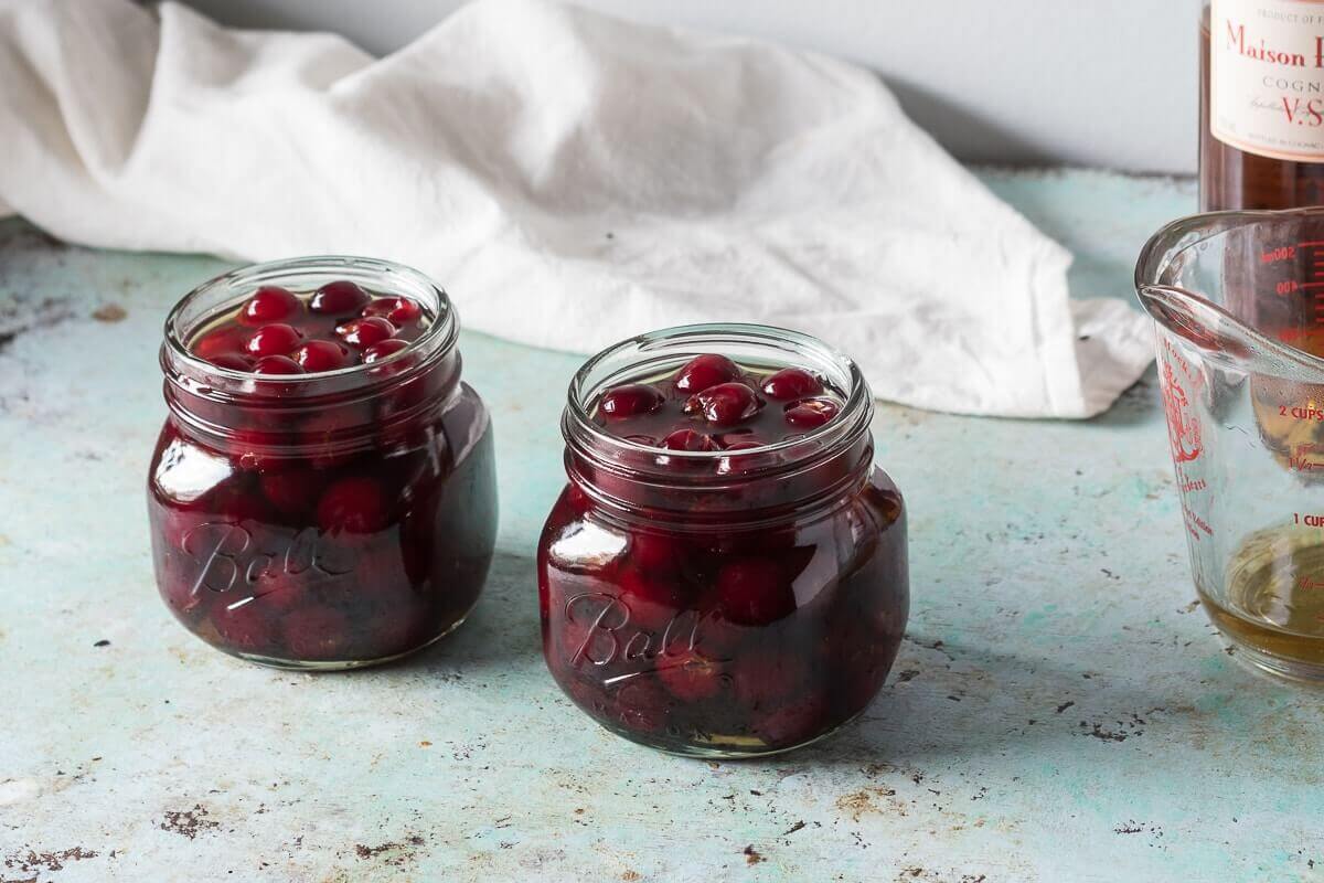 Brandied cherries in two glass ball jars.