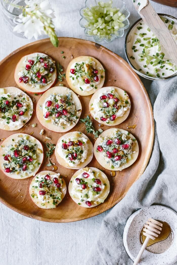 Apple slices topped with blue cheese, pomegranate seeds, and honey to make easy raw apple appetizers.