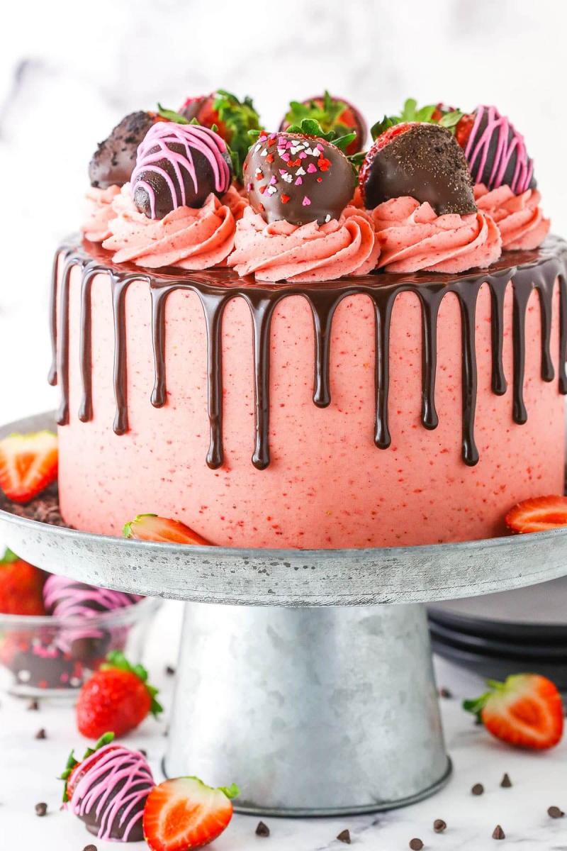 Chocolate covered strawberry cake decorated with strawberry frosting, chocolate ganache drip, and topped with chocolate covered strawberries.