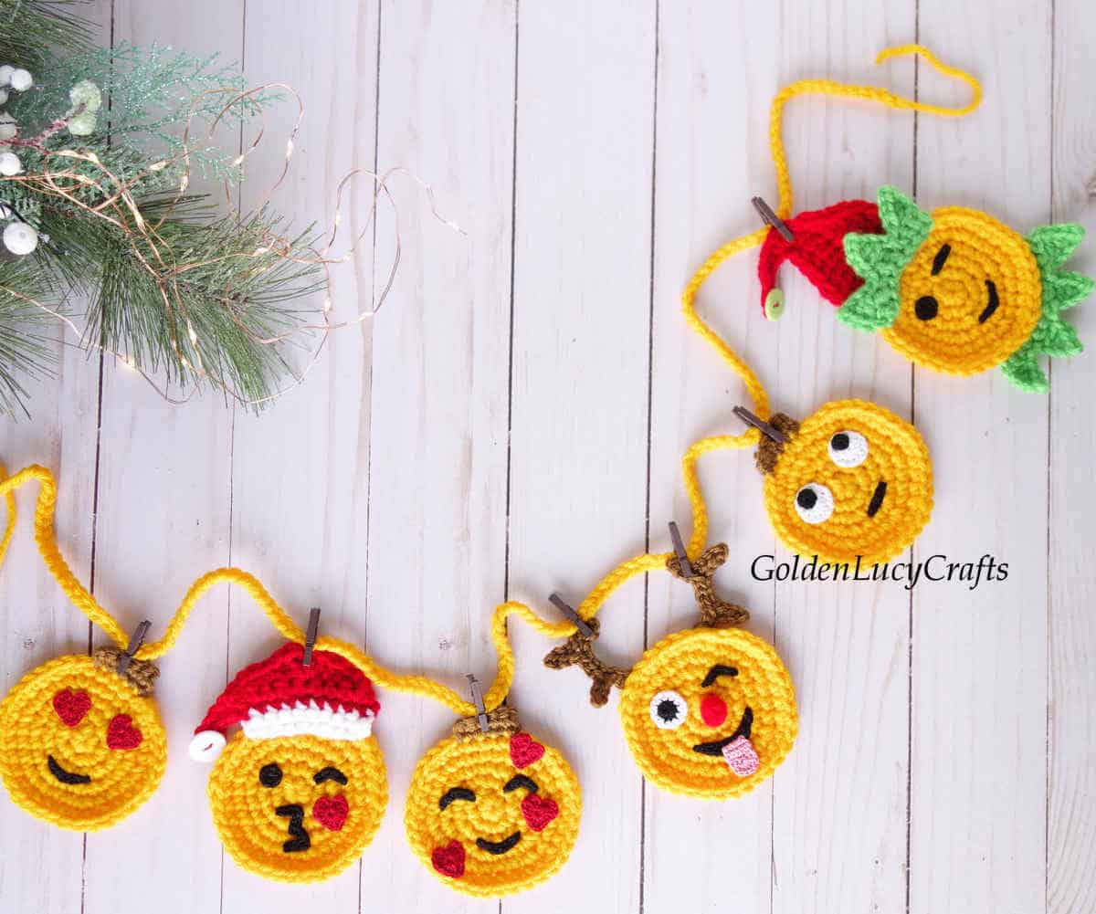 Crochet emoji Christmas garland on a white wooden background.