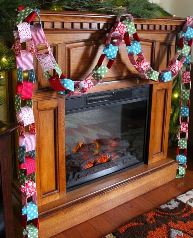 Chain christmas garland made from fabric, hung on a wooden fireplace mantel.