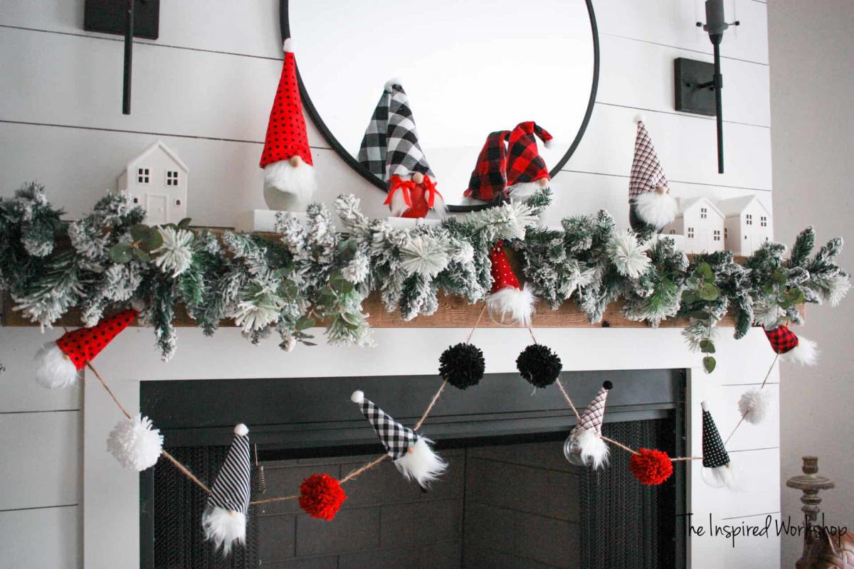 Gnome and yarn pom pom Christmas garland hanging from a fireplace mantel.