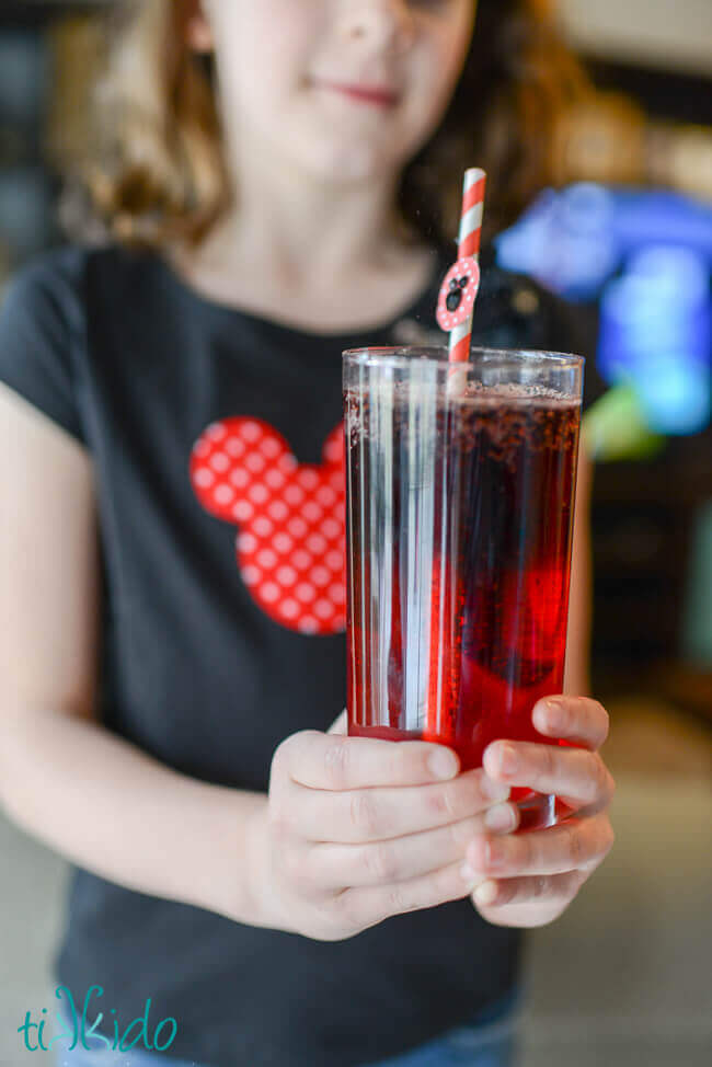 Girl holding a Mickey Mouse layered drink with a Mickey Mouse straw.