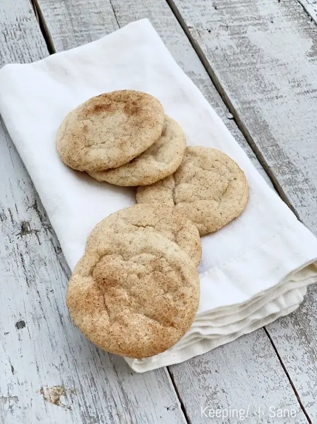 Eggless snickerdoodle cookies on a white cloth napkin on a wooden surface.