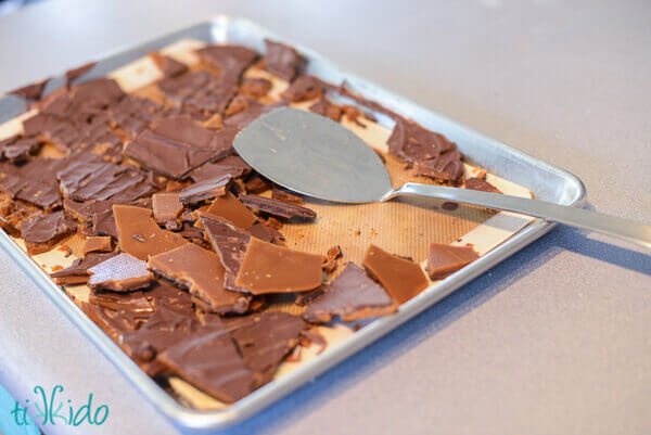 English toffee being broken into pieces with a metal spatula.
