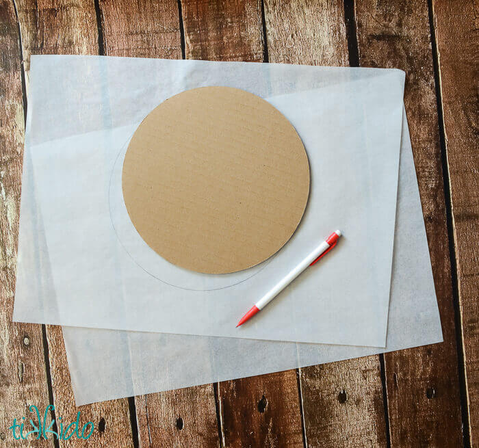 Parchment paper with a circle drawn on it, traced around a cake cardboard circle.
