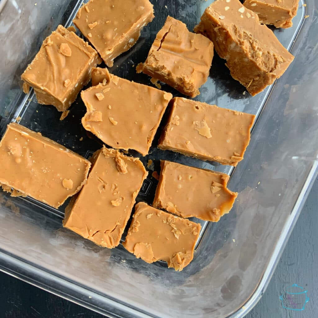 Pieces of slow cooker peanut butter fudge in a glass dish.