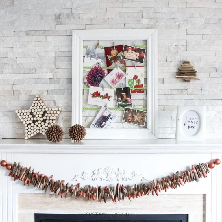 Christmas garland made from driftwood and copper paint hanging on a white fireplace mantel.