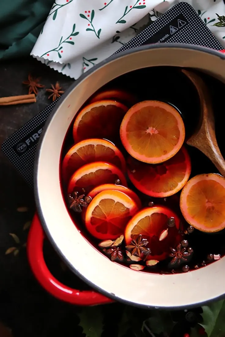 German mulled wine made in a crockpot, with floating orange slices and whole spices.