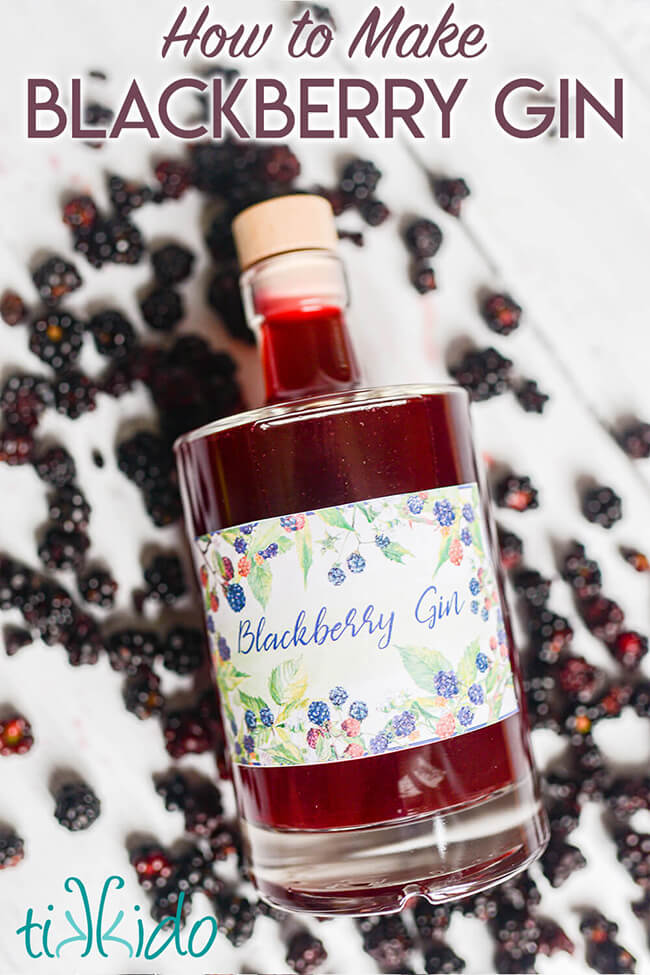 Bottle of homemade blackberry gin on a white wooden surface, surrounded by fresh blackberries, with text overlay reading "How to Make Blackberry Gin."