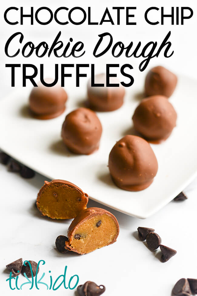 Chocolate chip cookie dough truffles arranged on a white plate, with one cut in half and sitting in front of the plate, with chocolate chips scattered around.