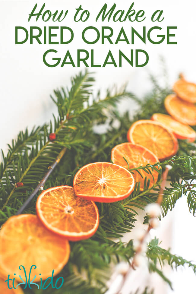 Dried orange garland on a bed of evergreen branches, with text overlay reading "How to Make a Dried Orange Garland."