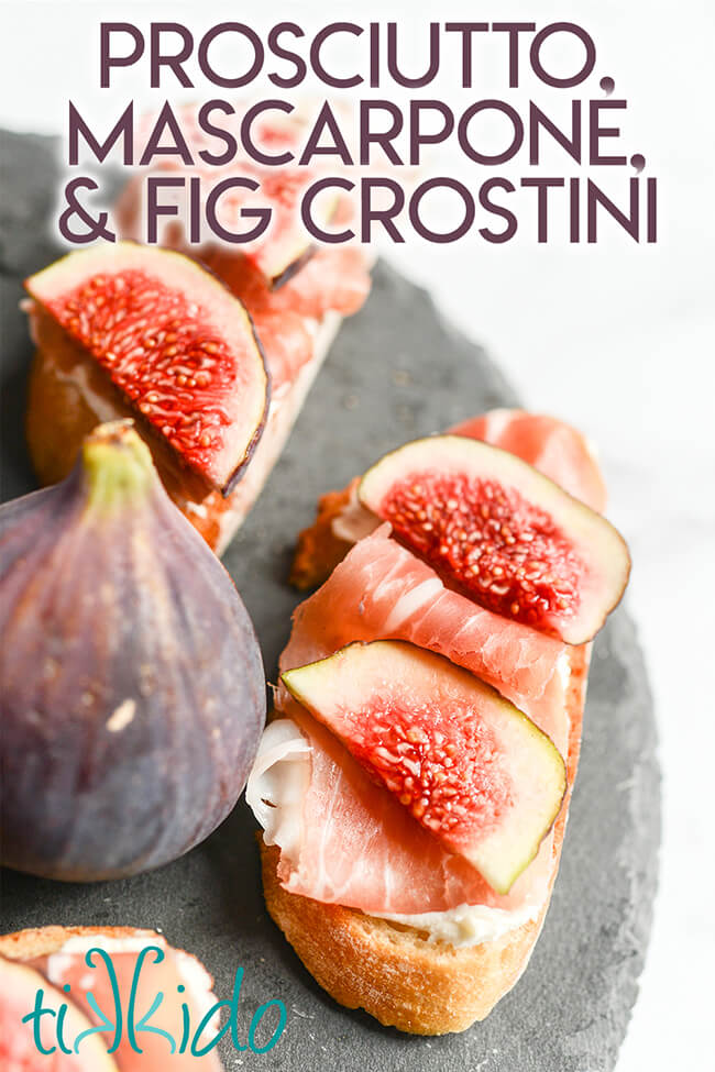 Fig, Prosciutto, and Mascarpone Crostini and fresh figs on a slate serving tray.