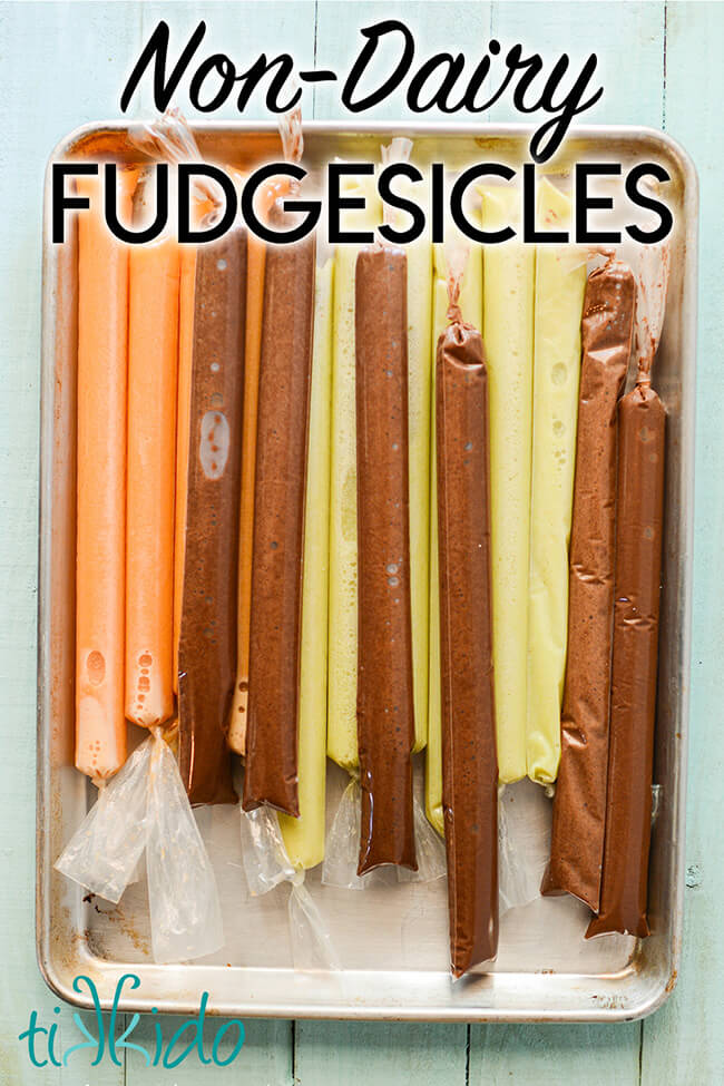 Vegan fudgesicles and vegan creamsicles popsicles frozen on a baking sheet, with text overlay reading "Non-Dairy Fudgesicles."
