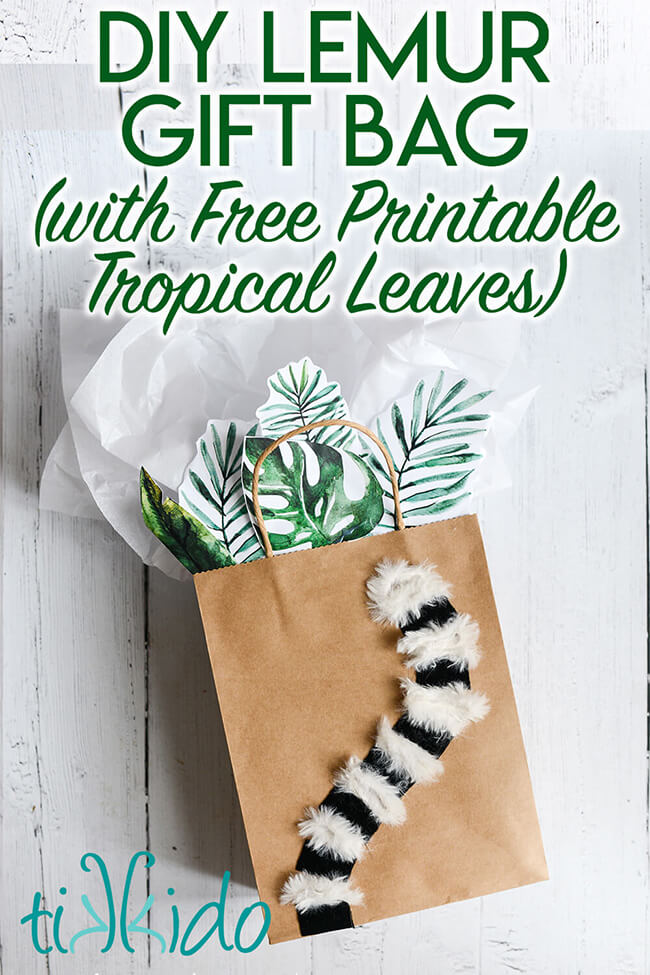Gift bag decorated with a furry lemur tail and tropical leaves, with text overlay reading "DIY lemur gift bag with free printable tropical leaves."