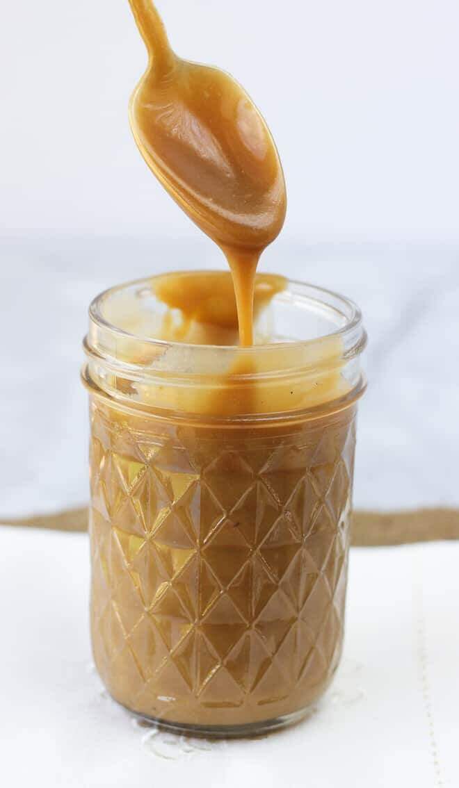 Dairy free, gluten free, paleo caramel sauce being spooned into a glass jar.