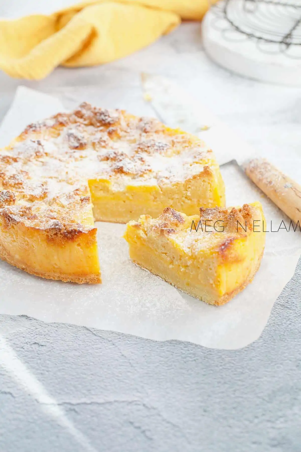 Low carb lemon curd cake on parchment paper, with a slice taken out of the cake.