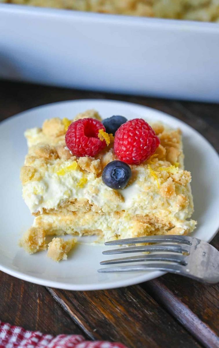 Slice of lemon icebox cake topped with fresh berries on a white plate.