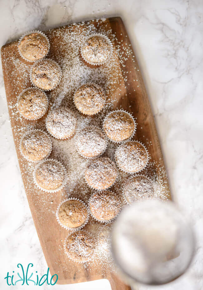 Mississippi spice muffins mini muffins being dusted with powdered sugar.