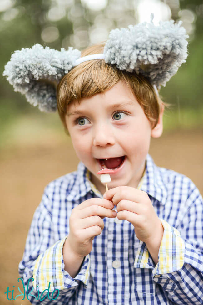 Little boy wearing wolf ears eating a chocolate mushroom.