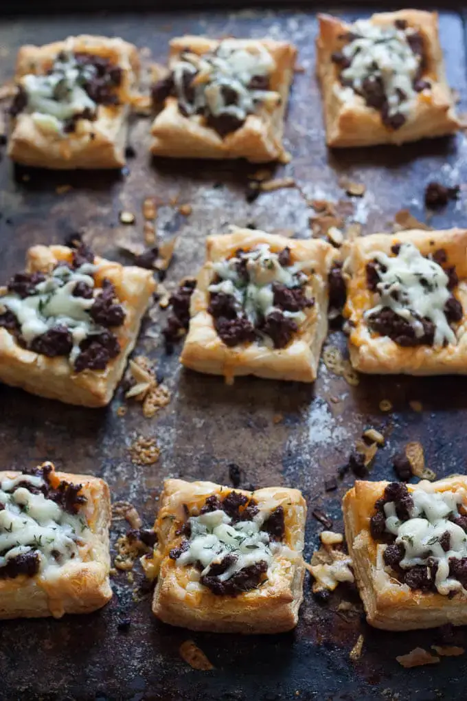 Cheesy chorizo apple tarts appetizers on a baking sheet.