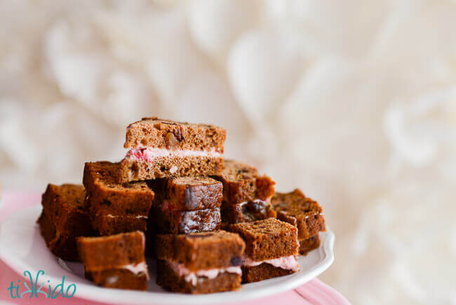 Date nut bread and strawberry cream cheese tea cakes on a white plate in front of a white textured background