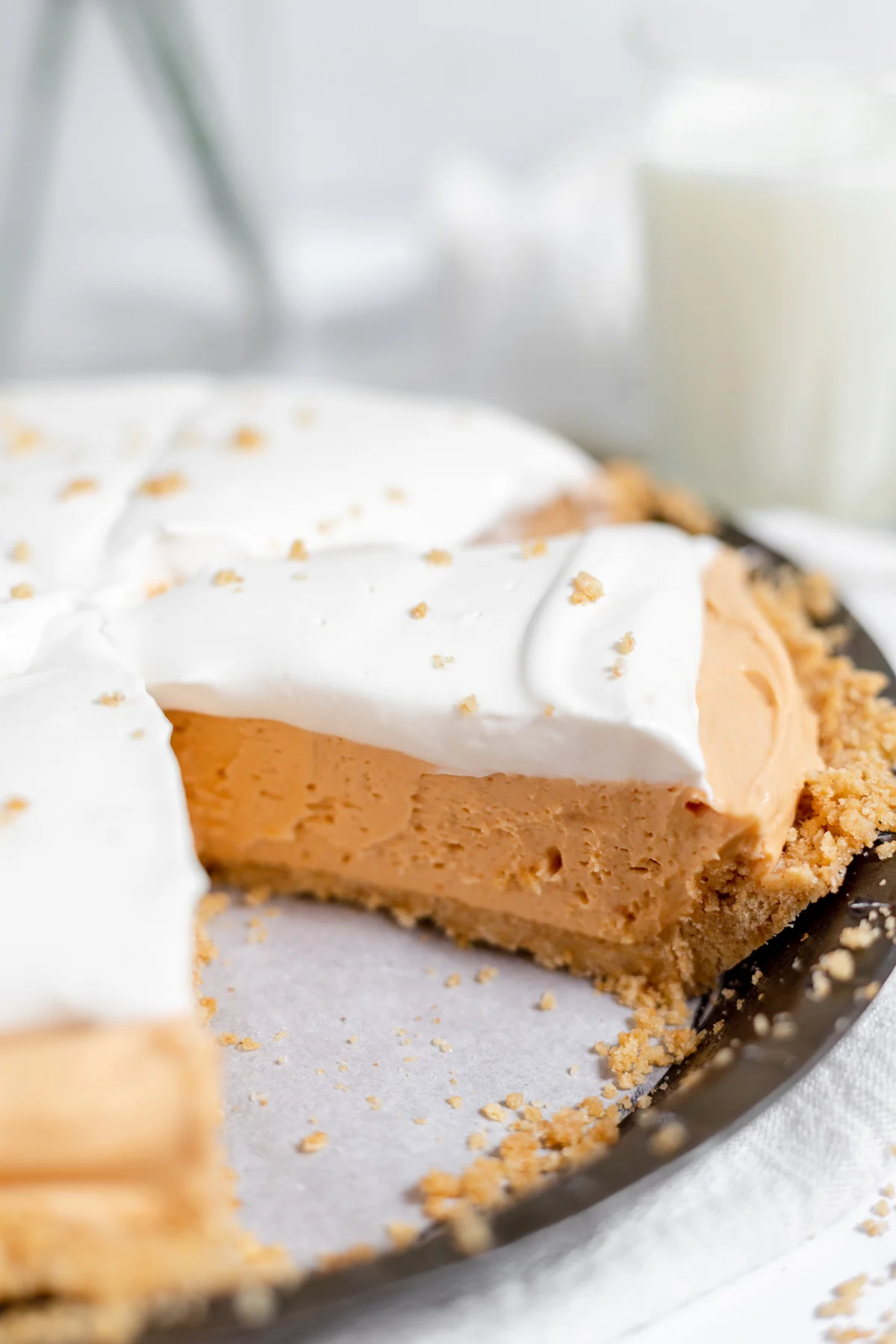 Old fashioned butterscotch pie in a pie plate, with one slice of pie missing.