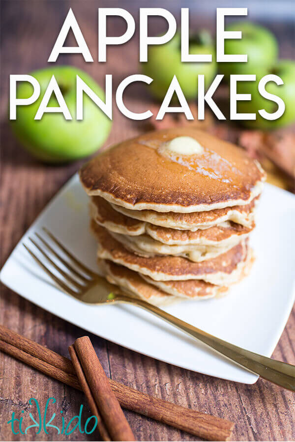 Stack of apple cinnamon pancakes on a white plate, surrounded by apples and cinnamon sticks, with a text overlay reading "Apple Pancakes."