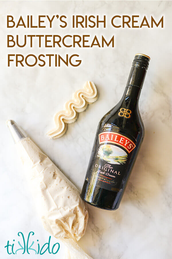 Bailey's frosting in a piping bag and swirled on a marble surface, next to a bottle of Bailey's Irish Cream.
