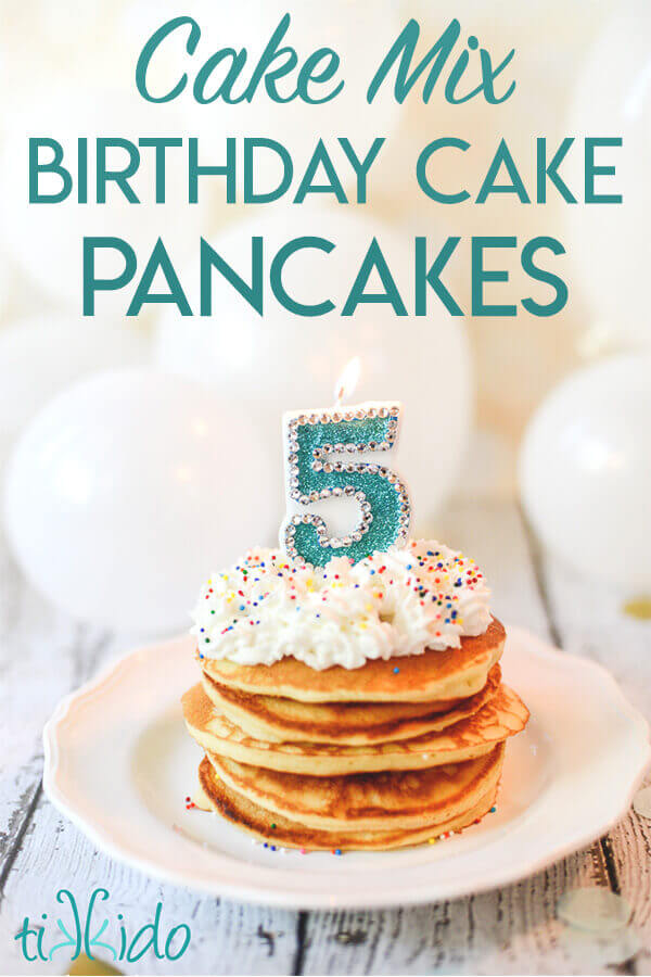 Stack of birthday cake pancakes with whipped cream, sprinkles, and a number 5 candle on top.
