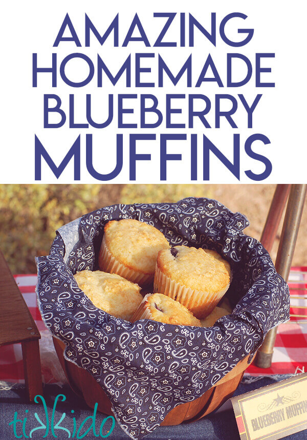 Blueberry muffins in a wooden basket lined with navy blue and white paisley print fabric on a red and white checked tablecloth.