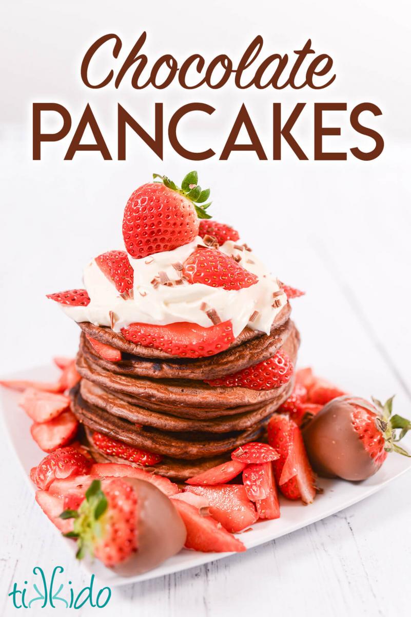 Stack of chocolate pancakes topped with whipped cream and fresh berries, with text overlay reading "chocolate pancakes."