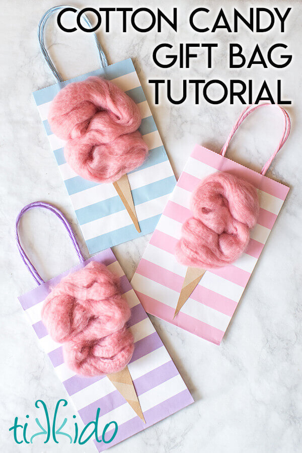 Three cotton candy party favor bags on a white marble background.