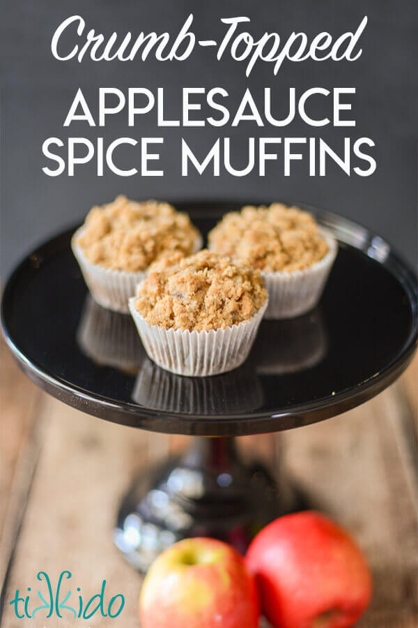 Three crumb topped applesauce spice muffins on a black cake plate.
