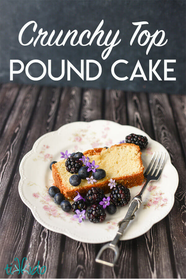 Pound Cake with blueberries, blackberries, and edible purple flowers on a floral plate on a dark wood background.