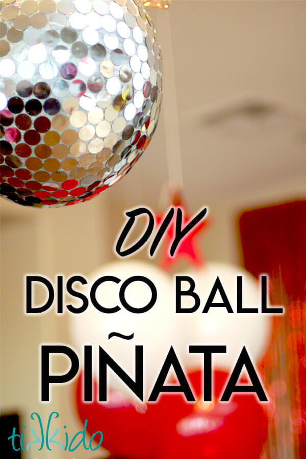 Disco ball piñata hanging above red and white balloons.
