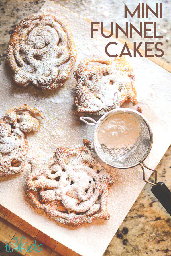 Homemade mini funnel cakes being dusted with powdered sugar.