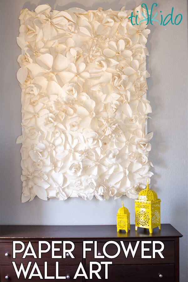 Large scale giant paper flower wall decoration made with white paper, hanging over a dark brown dresser.